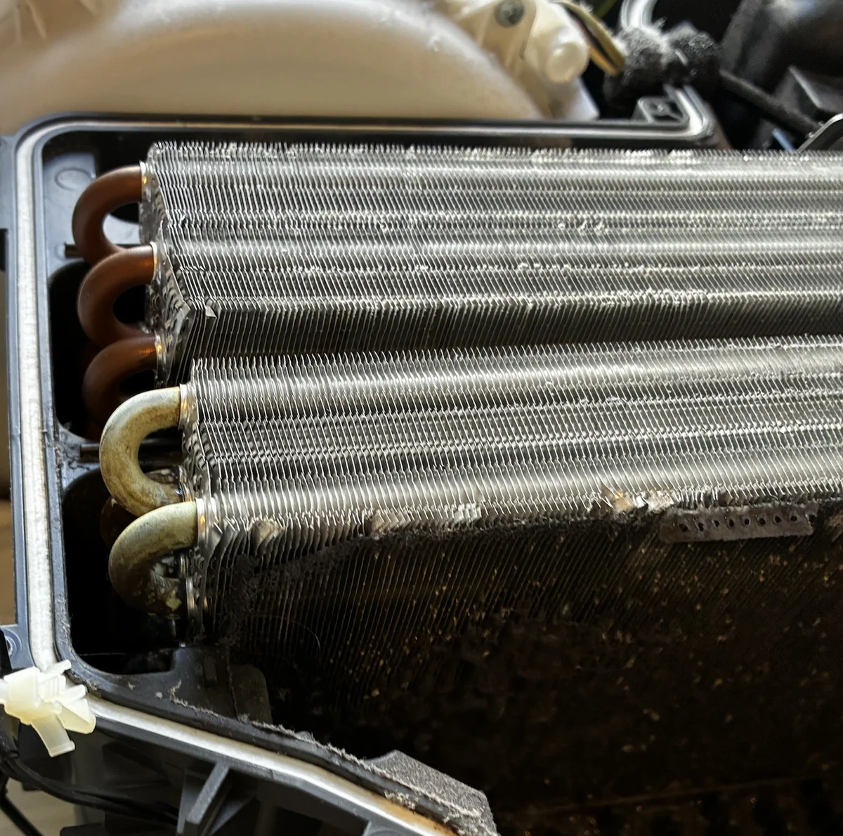 パナソニック NA-LX113B の乾燥用熱交換器。アルミのフィンの上半分は銀色できれいだが、下半分は糸くずとホコリで真っ黒に詰まっている